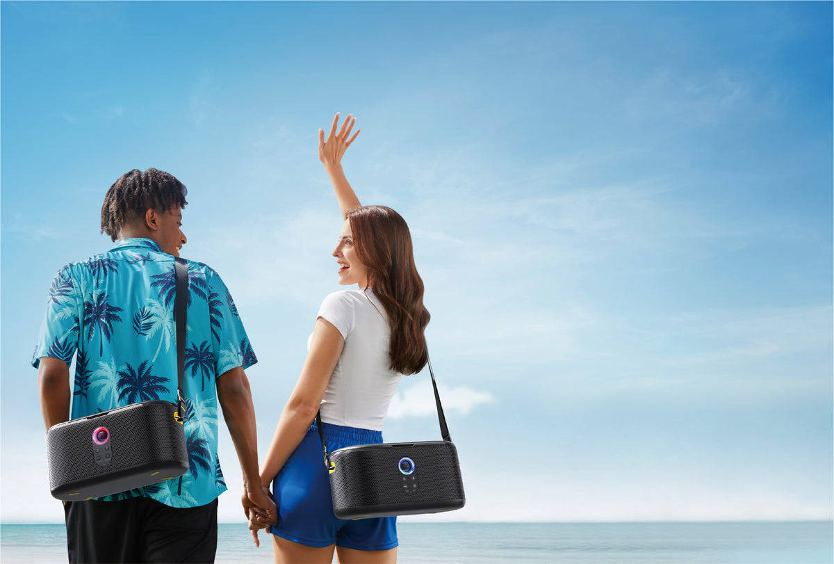 Two people carrying portable Ikarao karaoke machines by the sea